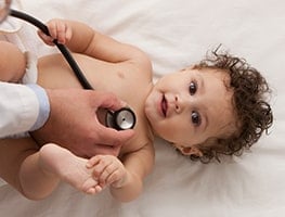 Doctor holding a stethoscope to a baby's chest