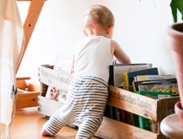 Baby looking into a bookshelf