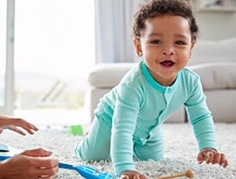 Smiling baby crawling on a rug