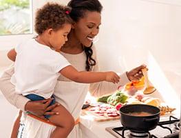 Toddler helping smiling mom to prepare food