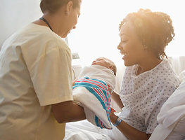 Nurse handing a woman her newborn baby
