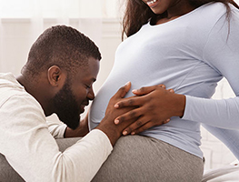 Man kissing his partner's pregnant belly