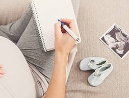 Pregnant woman with notepad and pen