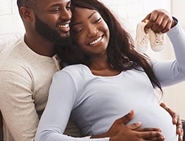 Smiling man and woman looking at baby shoes