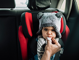 Baby wearing a furry hat sitting in a car safety chair