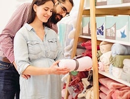Mom-and dad-to-be holding a pink blanket in a store