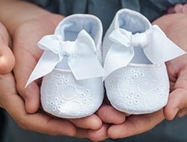 Parents holding a pair of baby shoes