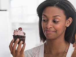 Pregnant woman giving a cupcake a sideward glance
