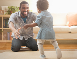 Baby walking to dad's outstretched hands