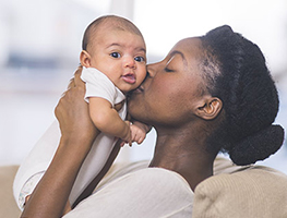 Mom kissing and holding up her newborn baby