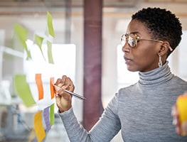 Woman writing on sticky notes on a board