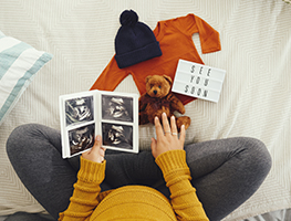 Woman looking at ultrasound photos and a teddy bear