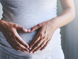 Pregnant woman's hands forming a heart shape over her belly