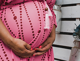 Woman in pink dress holding her pregnant belly