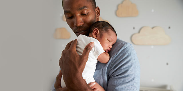 Dad holding a sleeping newborn baby on his shoulder
