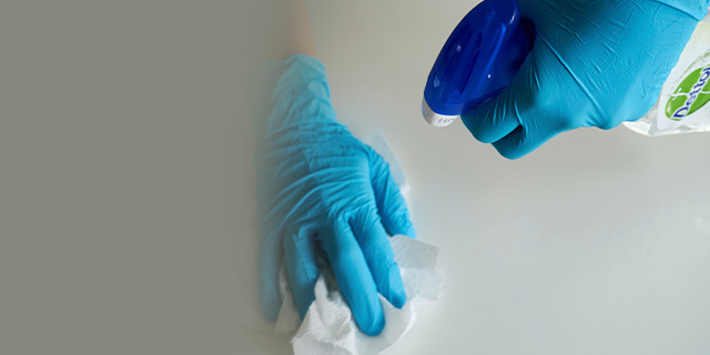 Gloved hands cleaning a surface