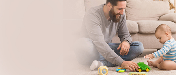 Man sitting on the floor next to a baby with toys