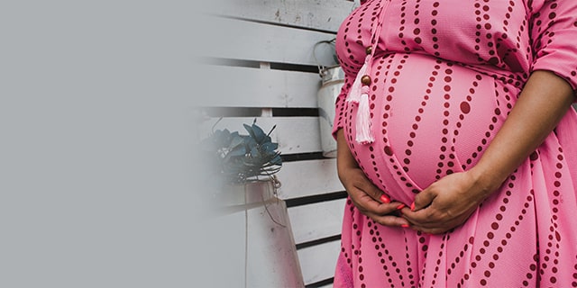 Woman in pink dress holding her pregnant belly