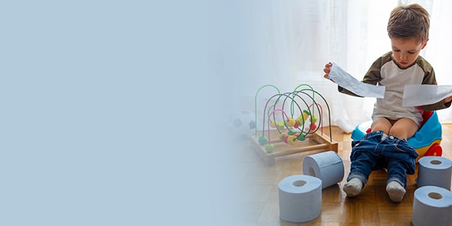 Toddler sitting on a toilet training seat and playing with toilet paper 